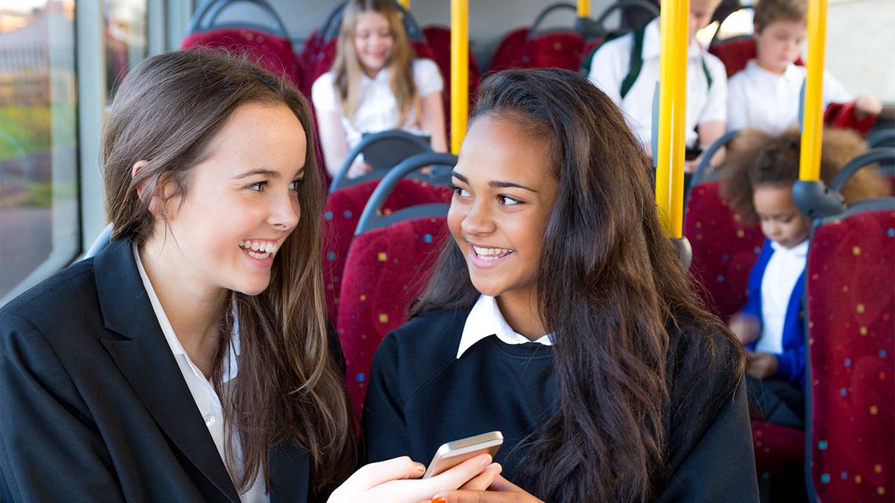 Group of students sitting and smiling on a bus