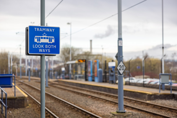 Photo of a sign next to a tram stop stating 'Tramway look both ways'