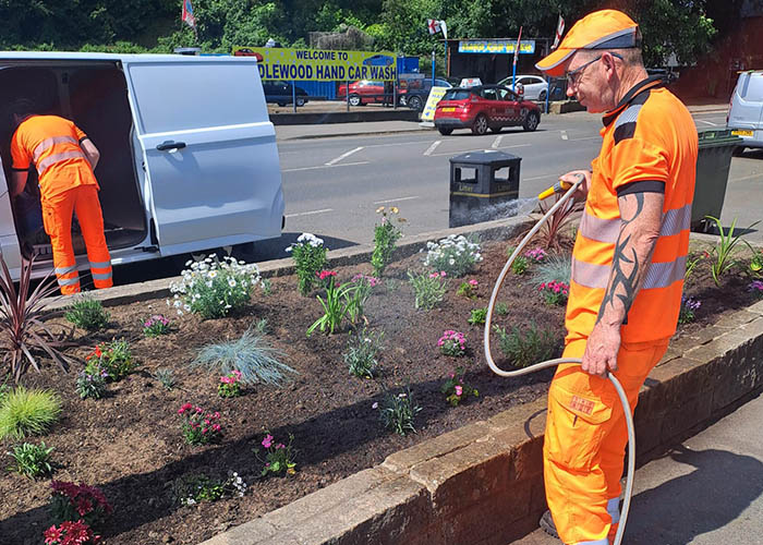 Volunteer watering flowers after planting at Middlewood