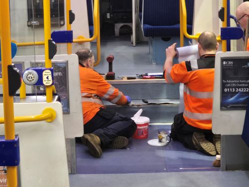 A team of two carefully removing overhead panels and signage to clear built-up dust and dirt