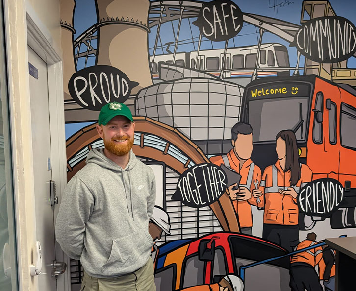 Luke Horton at Supertram office with his design in the background