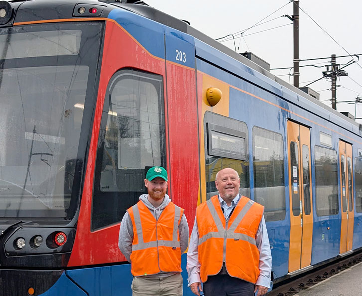 Luke and Supertram colleague in hi-vis vest standing beside Supertram
