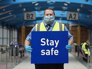 Interchange member of staff with sign saying ' Stay Safe'