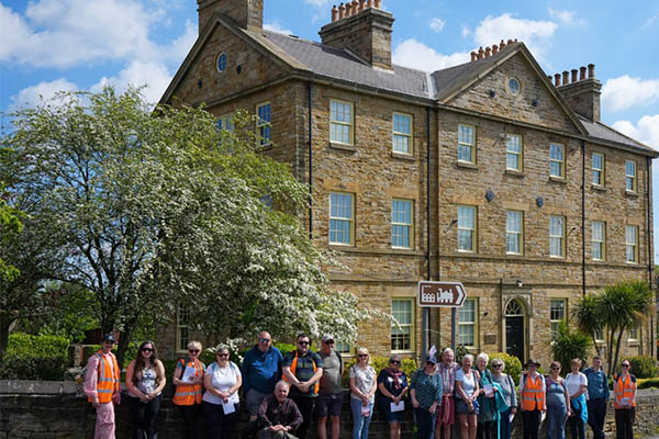 A large group of around 25 participants posed together in front of Fitzwilliam Lodge
