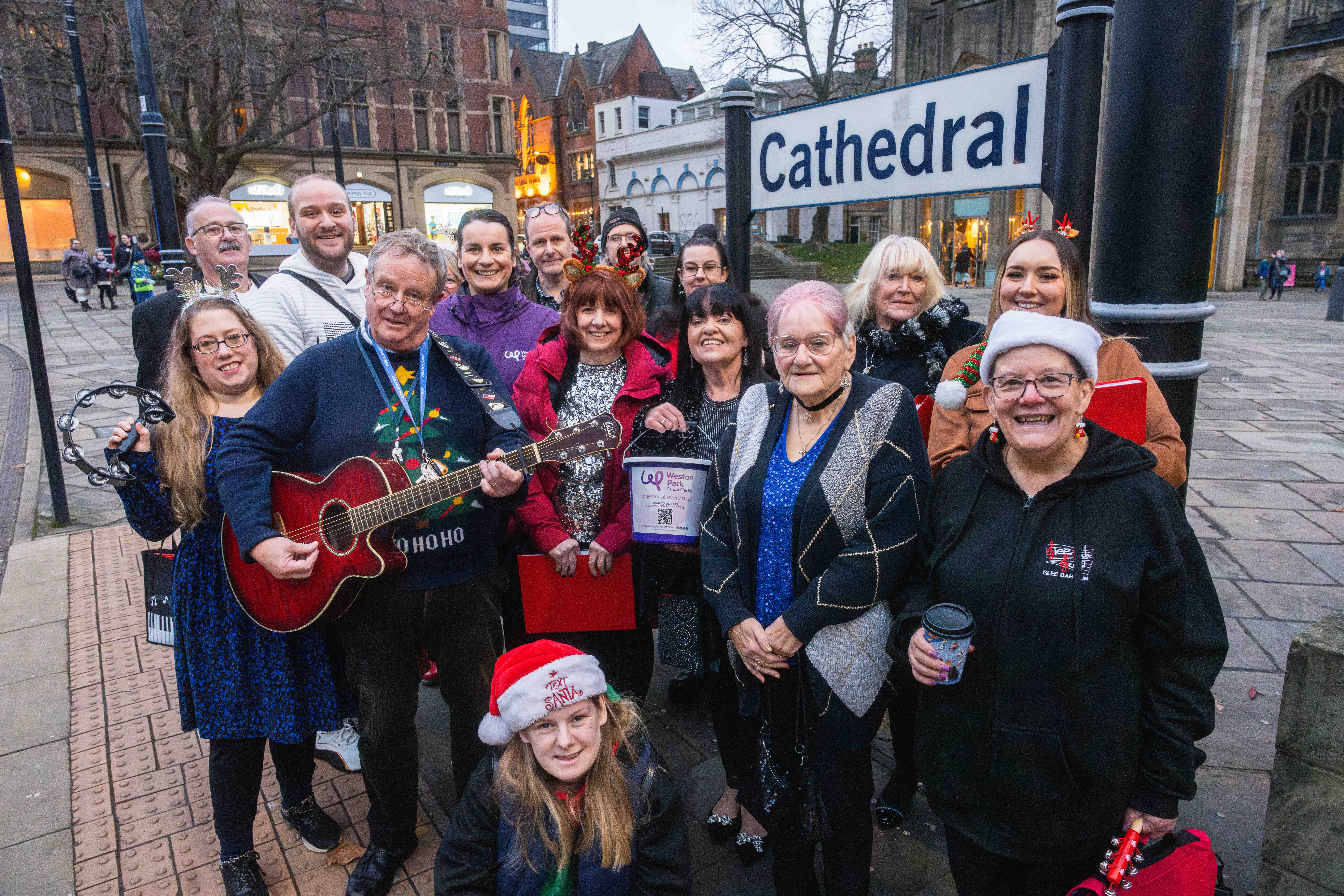 Carol singers smiling at Cathedral tram stop