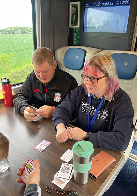 young people and the volunteer playing a card game on the train