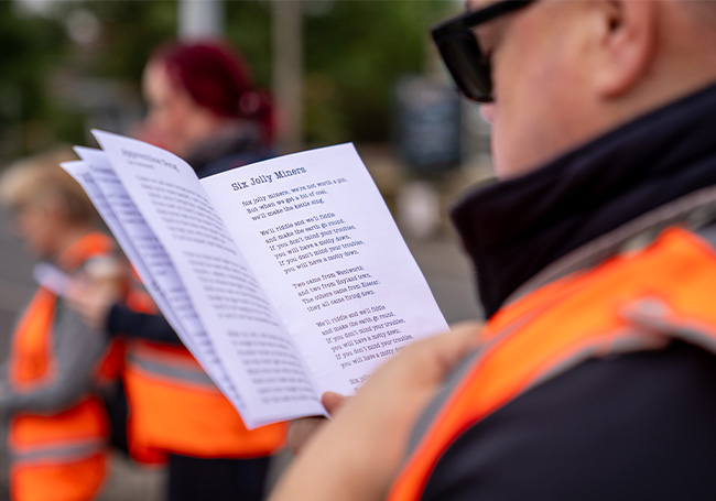 Participant singing from a song booklet during the walk