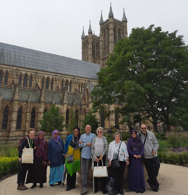 group of eight rail trip travellers stood facing the camera in front of Lincoln cathedral