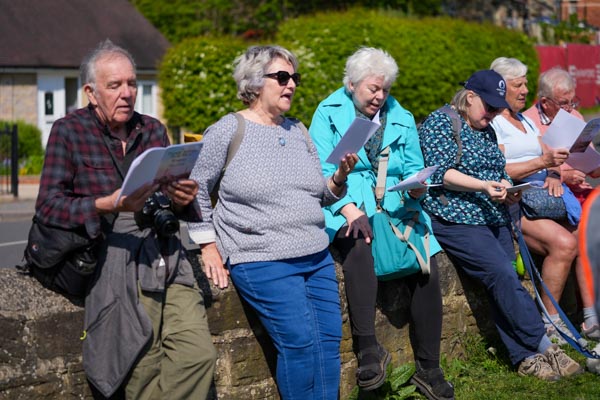 Four participants reading from song sheets in the sunshine