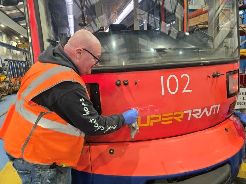 A team polishing and buffing the tram exterior to restore shine and presentation